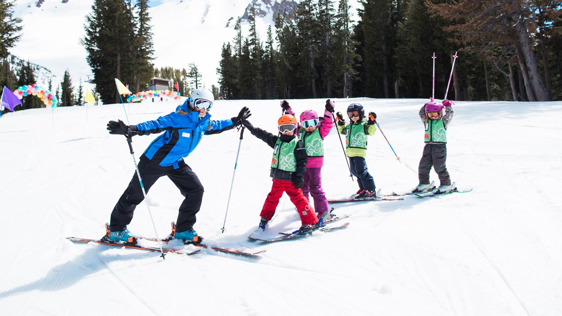 A ski instructor high-fives children at Mammoth Mountain