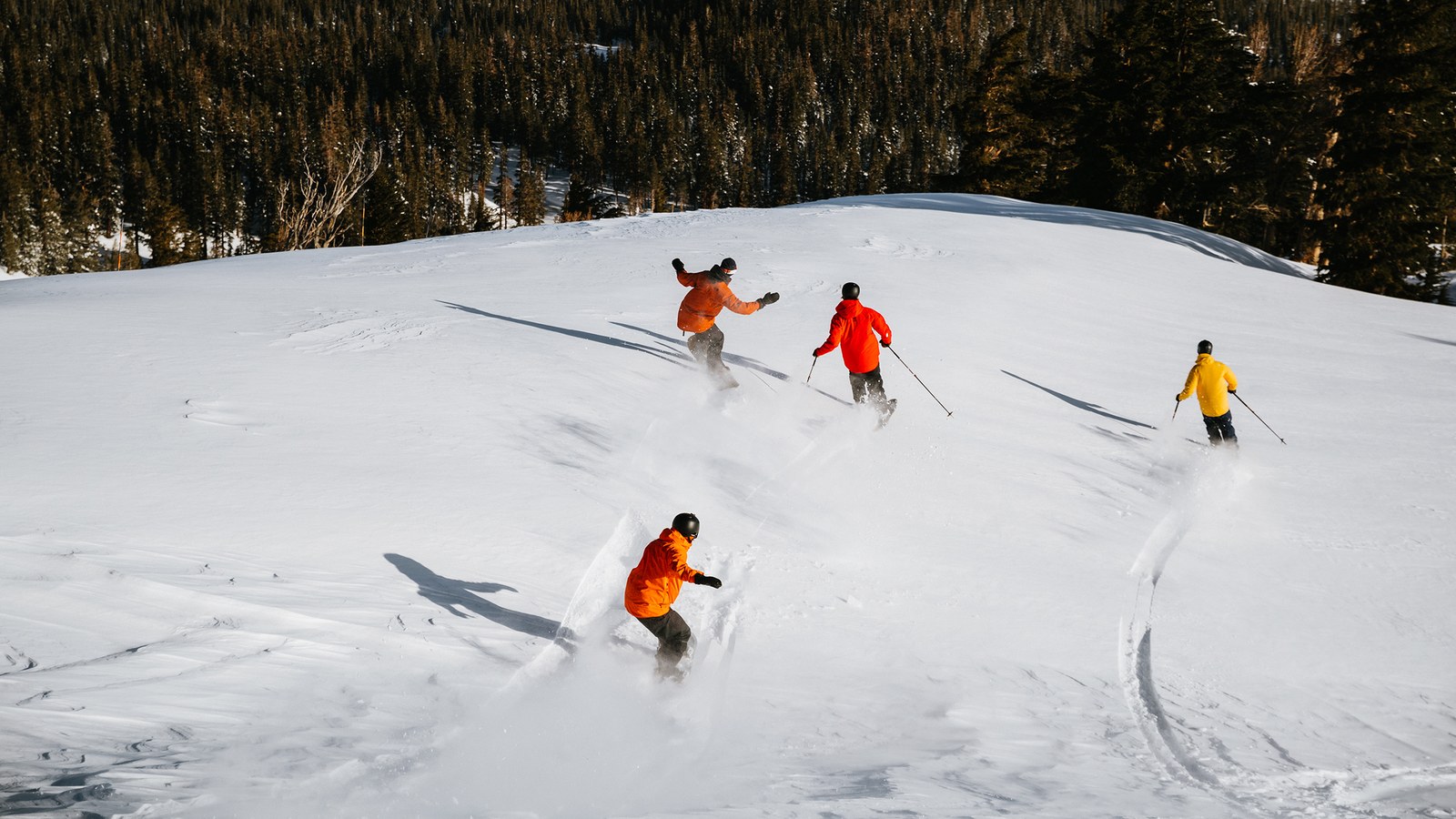 Skiers and snowboarders descend a snowy slope at Mammoth Mountain